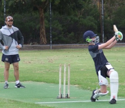 Declan Scott hits out on the centre wicket, under the watchful eye of senior quick Alex Davidson.