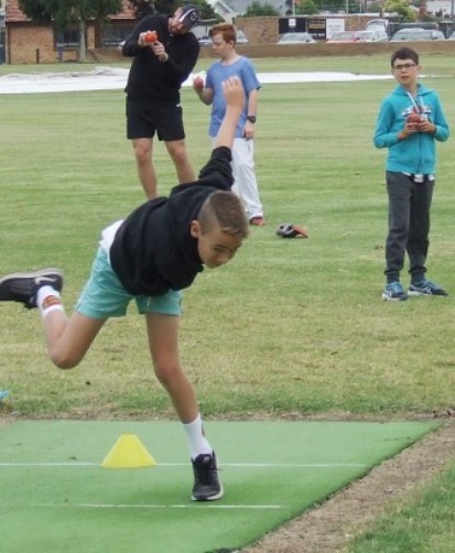 Lachie Monger puts his shoulder into his bowling, with Firsts captain Nate Wolland and junior teammates Nick Padden and Callum Morrissy in the background.