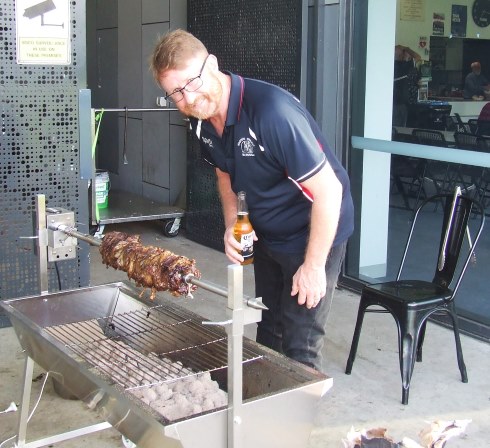 Master chef Dean Lawson checks on the spit roast outside the pavilion.